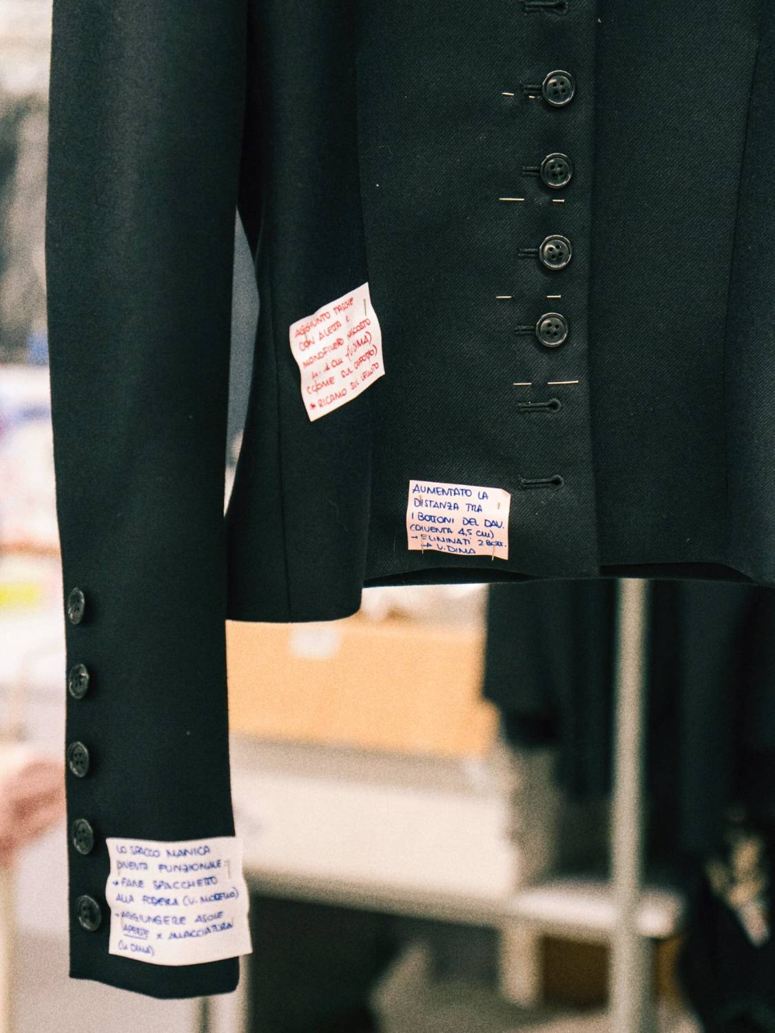 Atelier notes pinned to a jacket during fitting